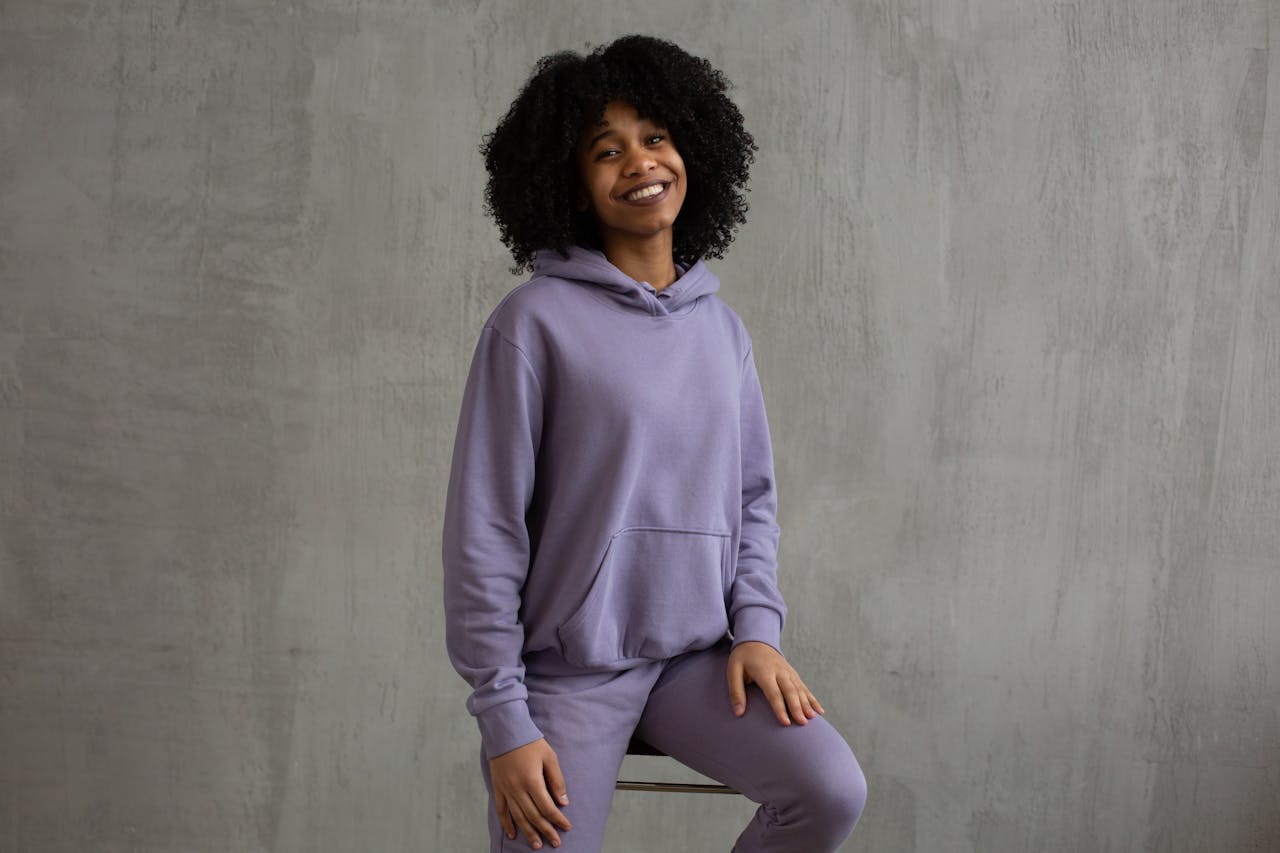 why-choose-us Cheerful young woman wearing casual purple outfit, sitting indoors.